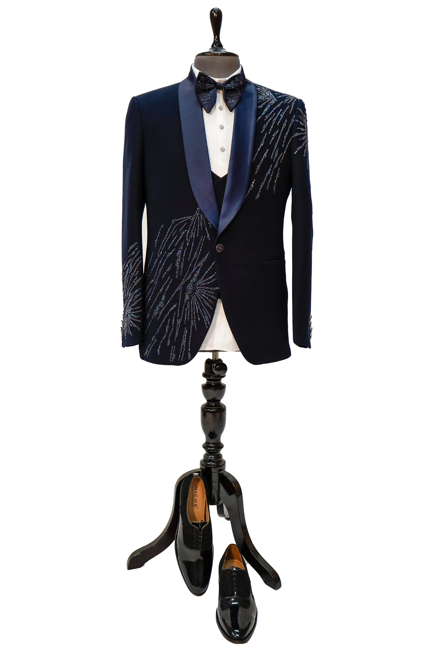 A navy blue tuxedo with vibrant colored curtdana embroidery displayed on a mannequin.
