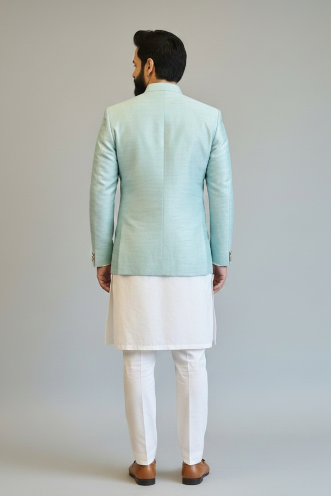 Man wearing a light blue jacket and white pants against a plain background