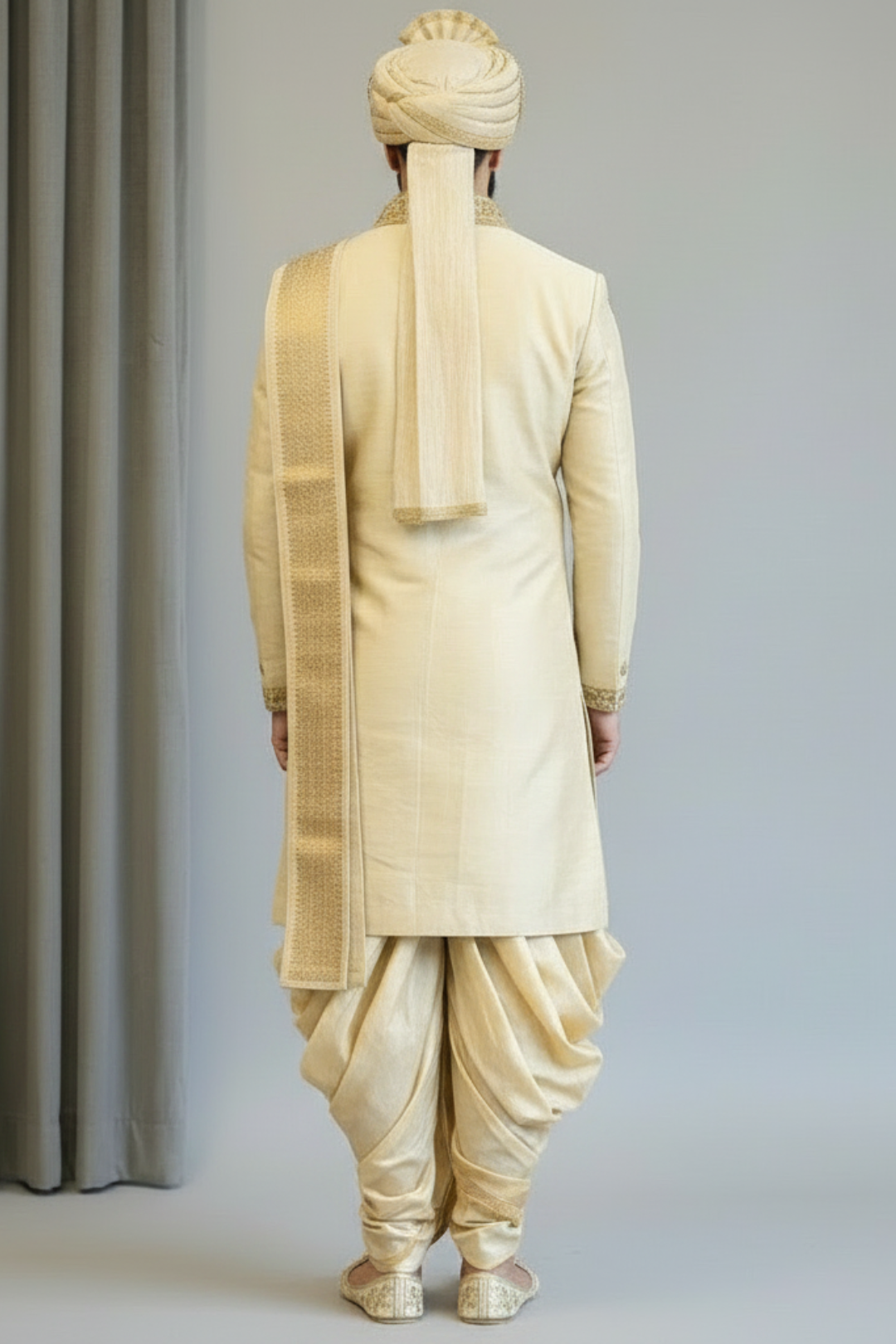 Man wearing a traditional cream-colored sherwani with a turban against a plain background