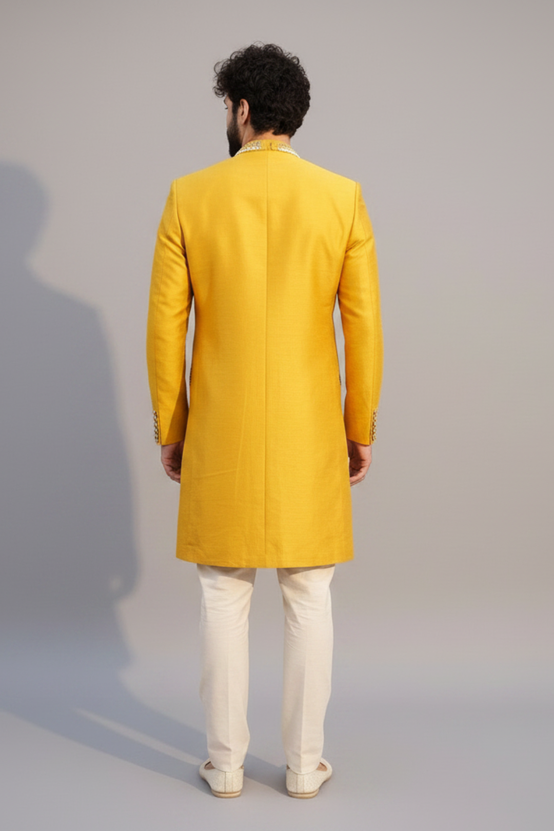 Man wearing a yellow traditional outfit against a gray background