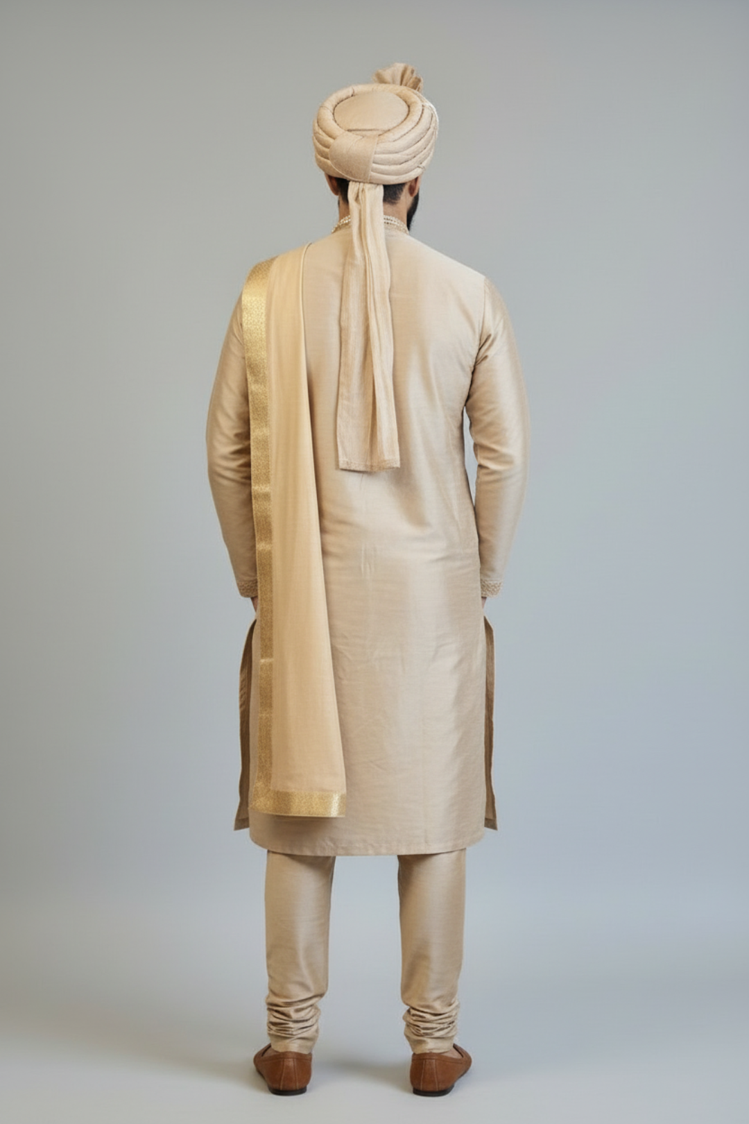 Man wearing a traditional beige kurta with a matching turban on a plain background