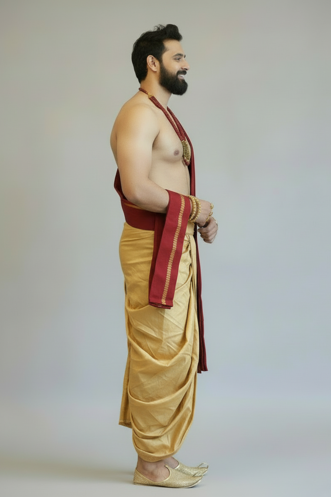 Man wearing a traditional gold dhoti with a red border on a plain background