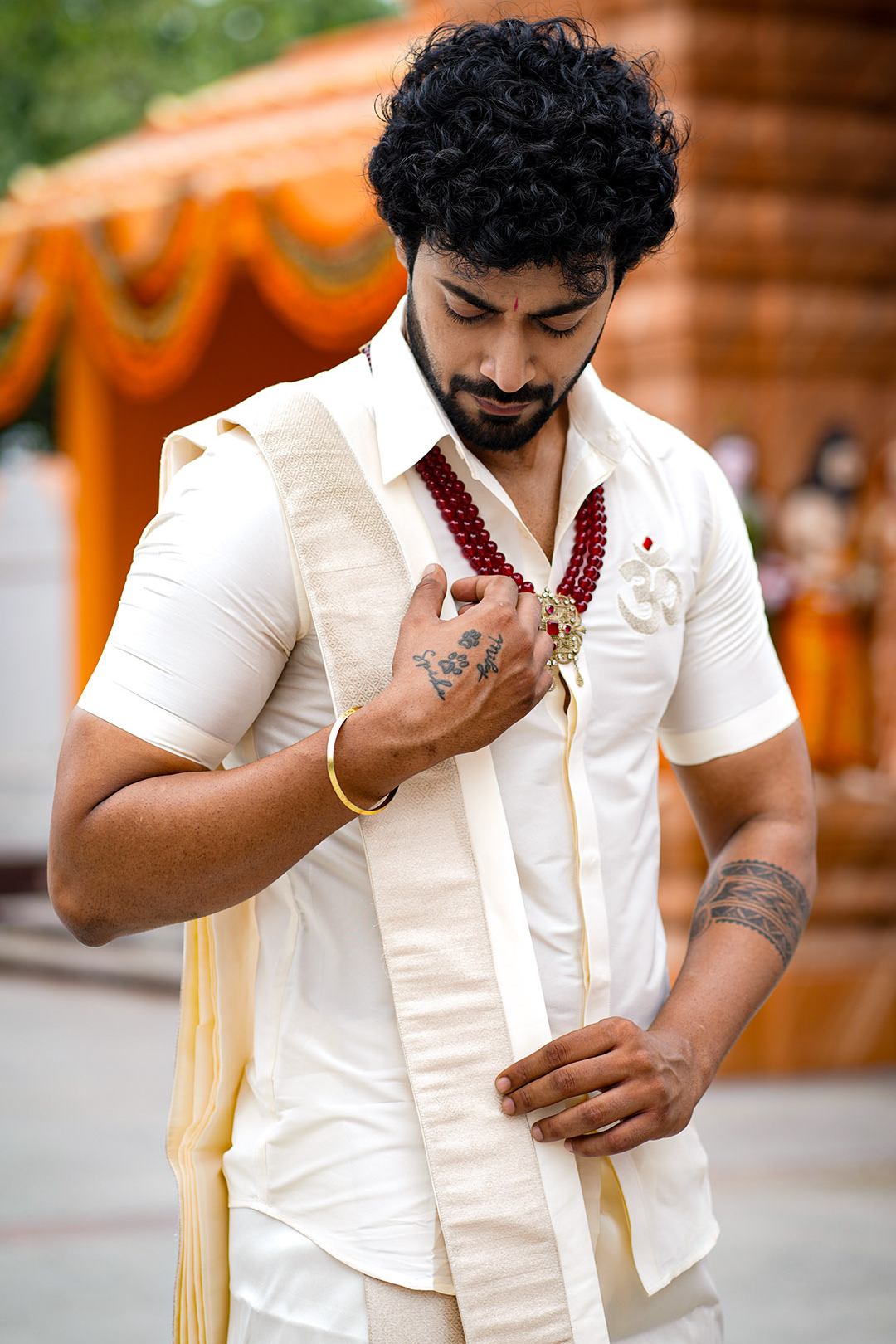 Man adjusting his necklace in a traditional setting