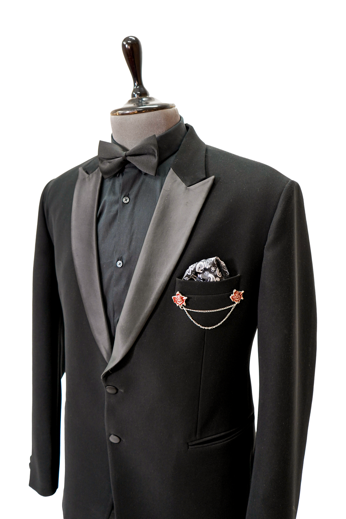 A black Italian woolcrepe peak lapel tuxedo on a mannequin, featuring a jacket and trousers with a classic design.