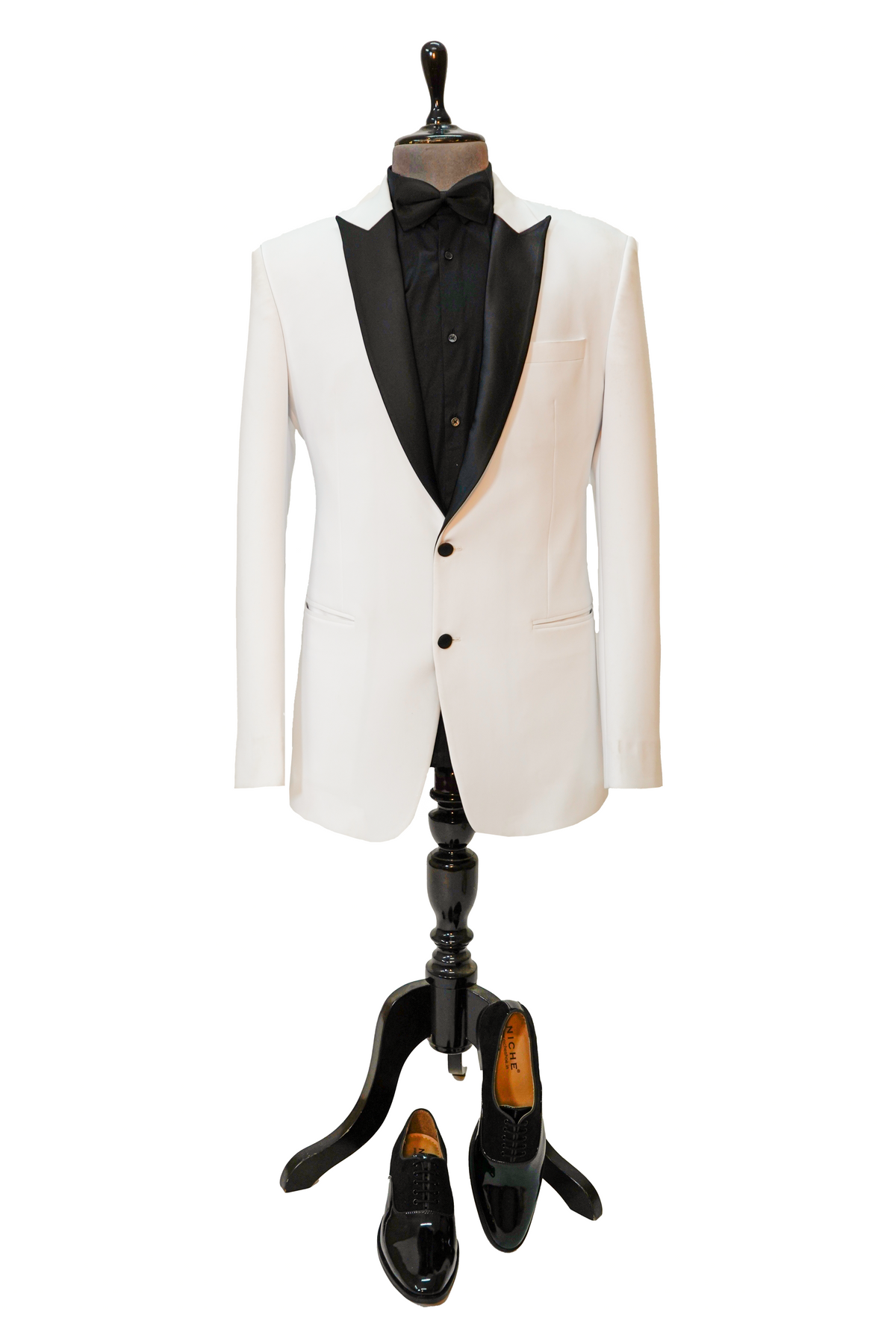 Man wearing a white blazer over a black shirt with black pants and shoes on a light gray background