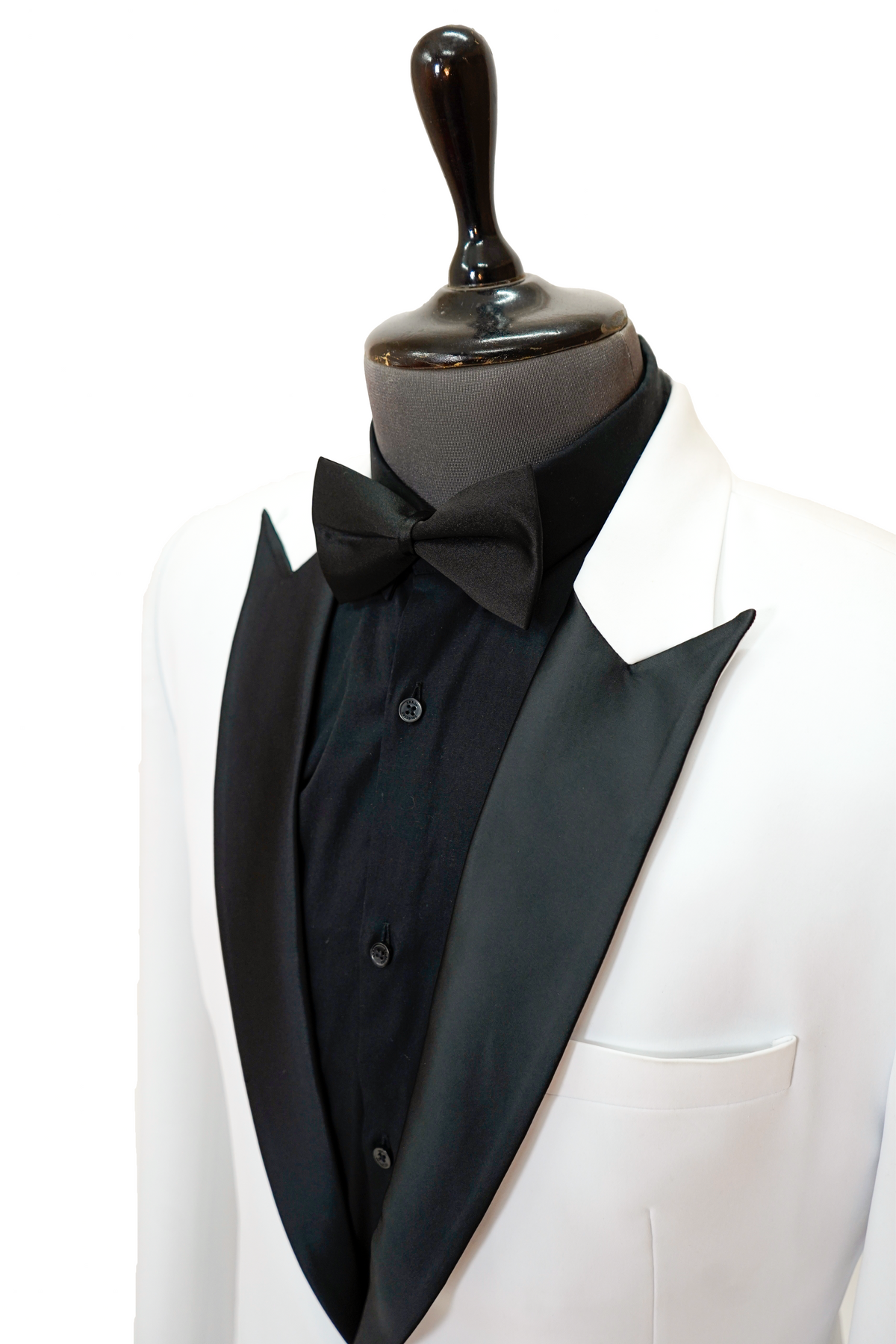 Man wearing a white blazer over a black shirt with black pants and shoes on a light gray background