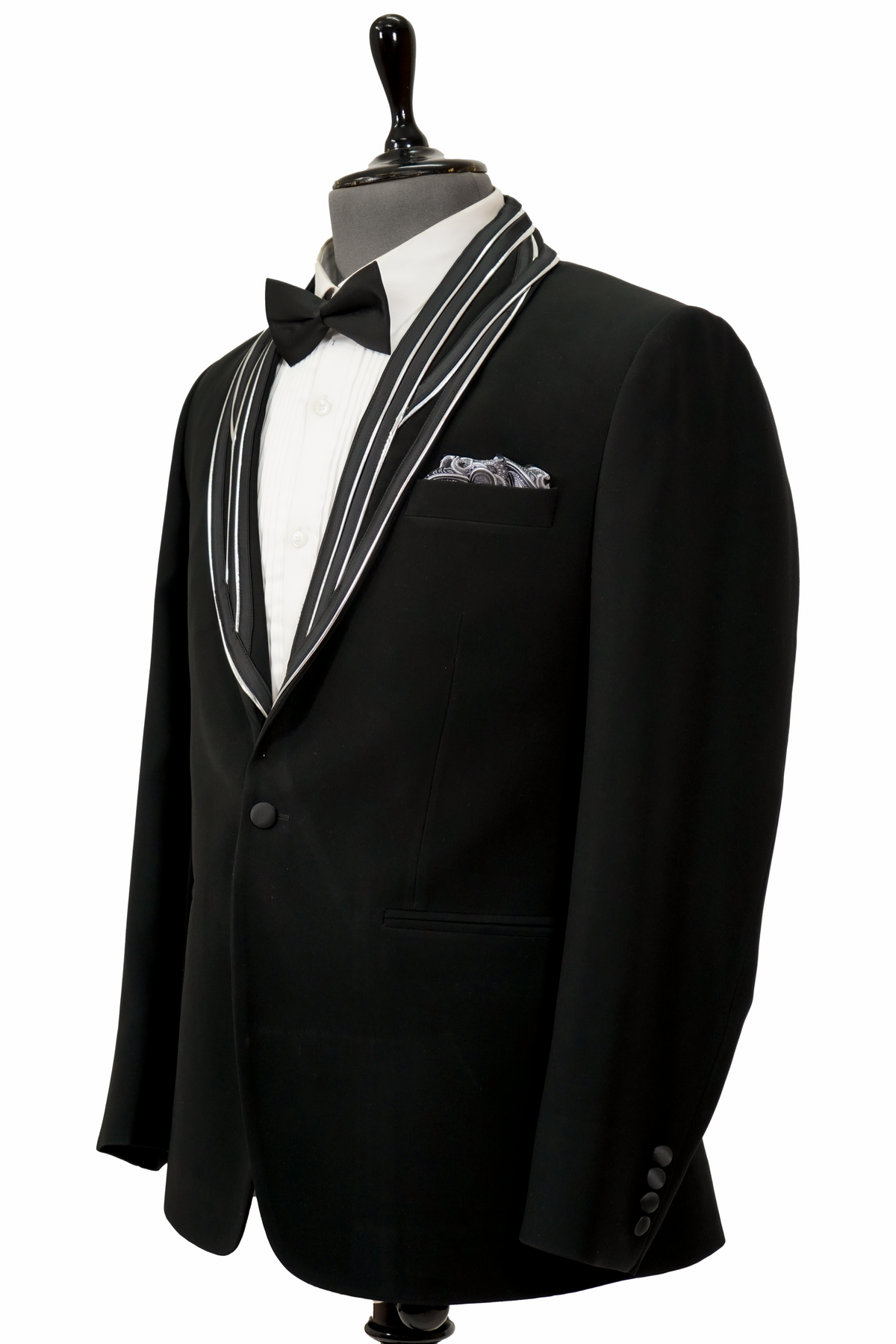 Man wearing a black tuxedo with a white shirt and bow tie on a gray background