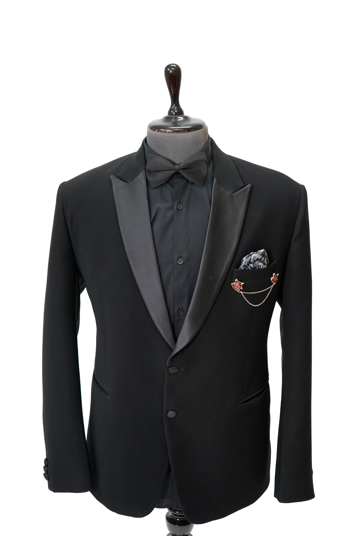 A black Italian woolcrepe peak lapel tuxedo on a mannequin, featuring a jacket and trousers with a classic design.