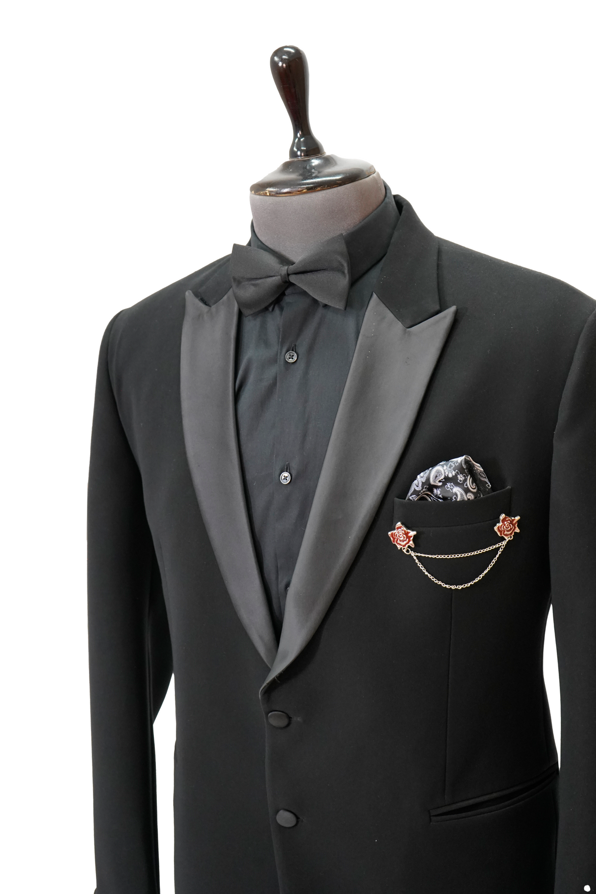 A black Italian woolcrepe peak lapel tuxedo on a mannequin, featuring a jacket and trousers with a classic design.