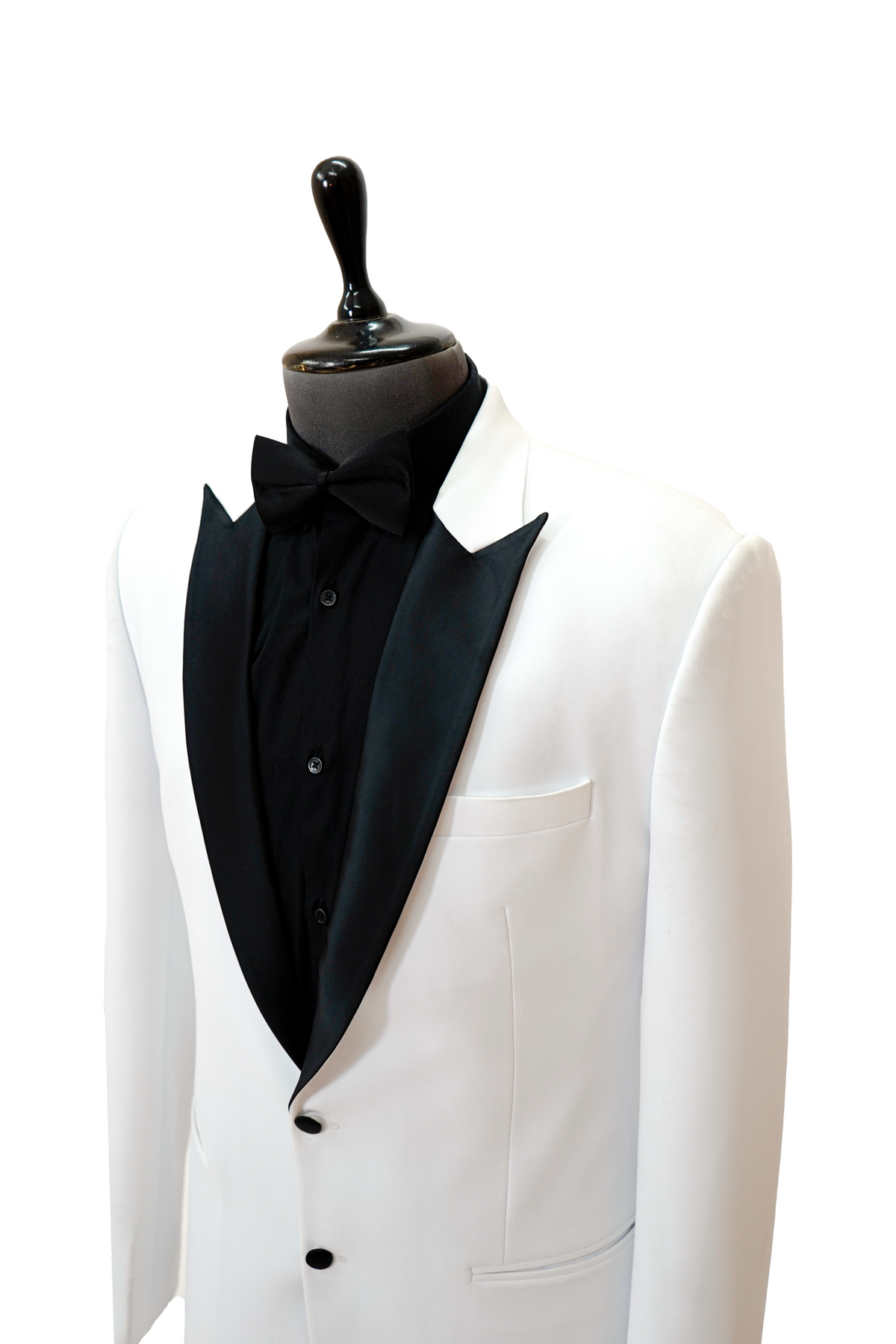 Man wearing a white blazer over a black shirt with black pants and shoes on a light gray background