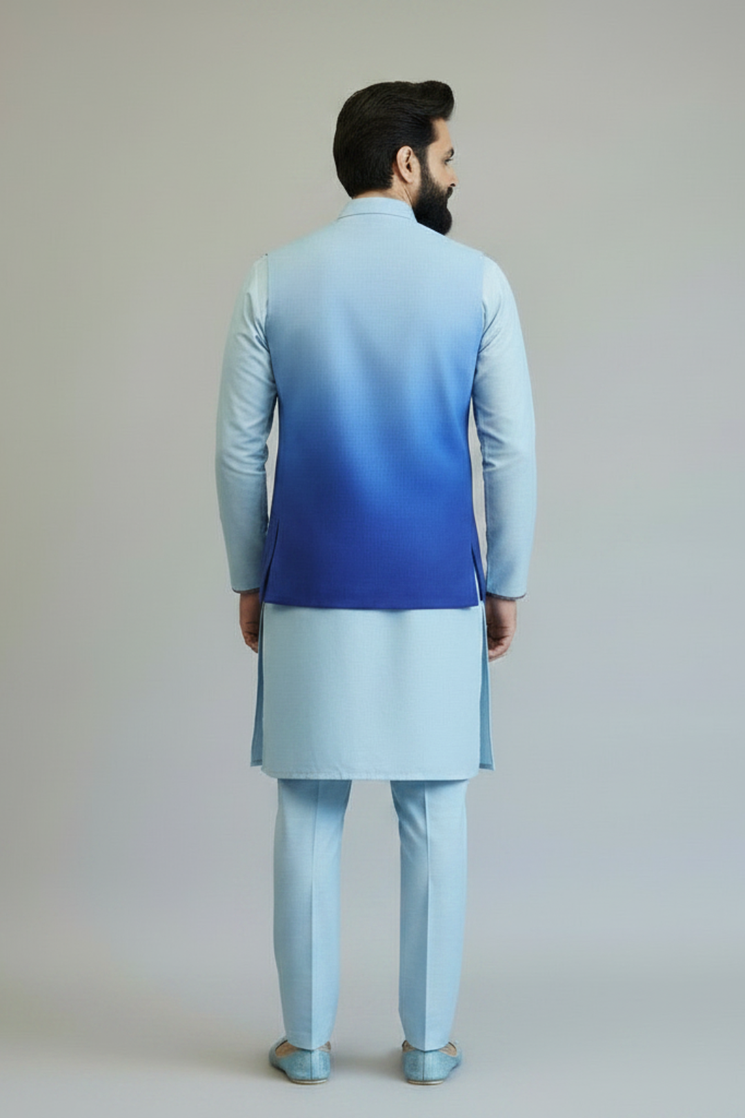 Man wearing a light blue and gray traditional outfit with a gradient effect on a plain background