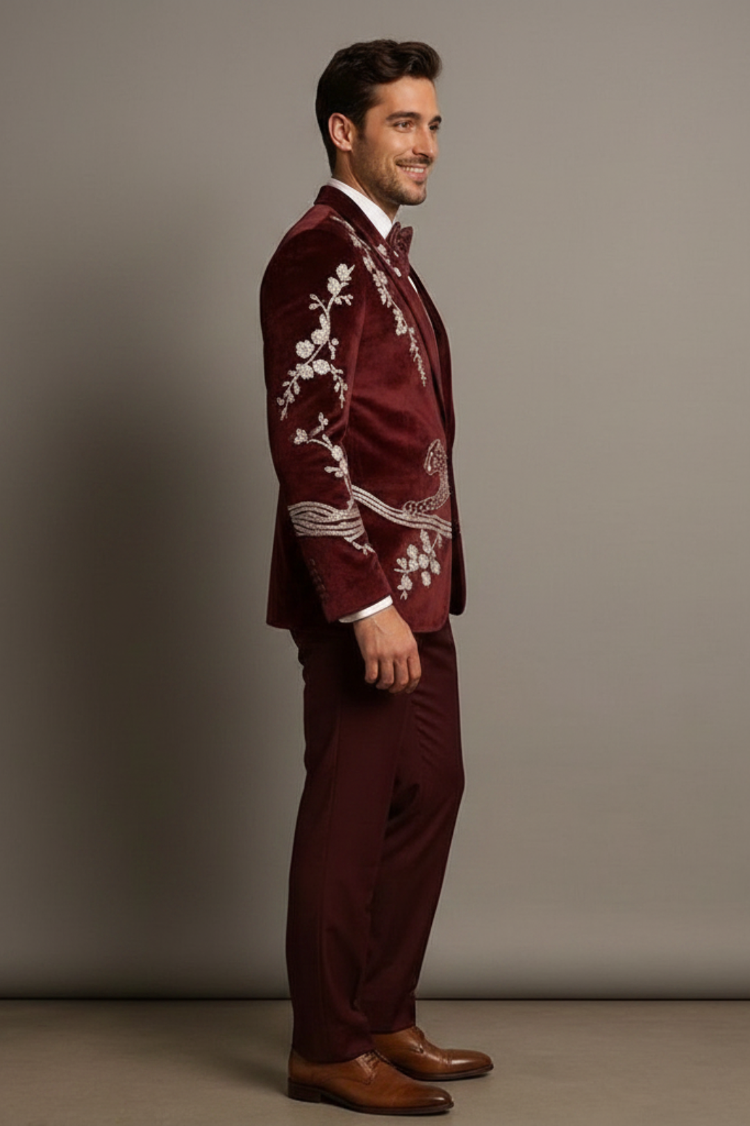 Man wearing a burgundy suit with white embroidery on a gray background