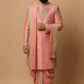 Man wearing a traditional pink sherwani with intricate designs on a beige background