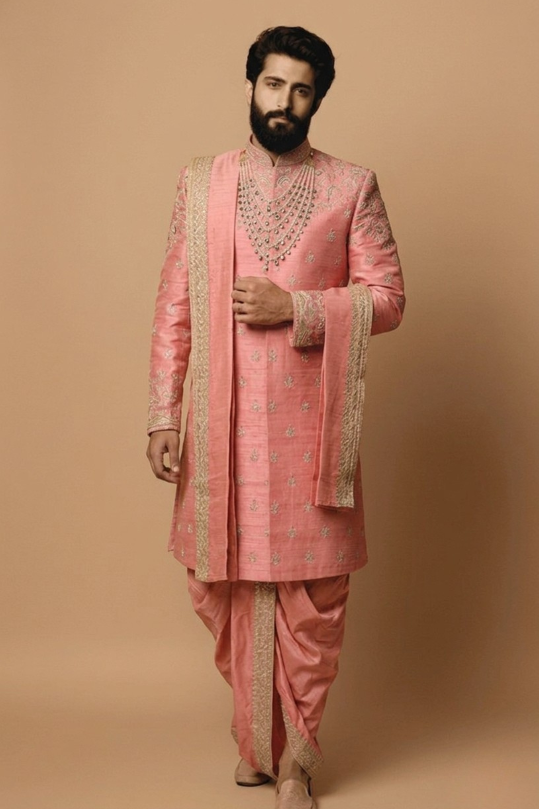 Man wearing a traditional pink sherwani with intricate designs on a beige background