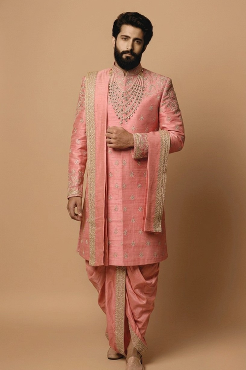 Man wearing a traditional pink sherwani with intricate designs on a beige background