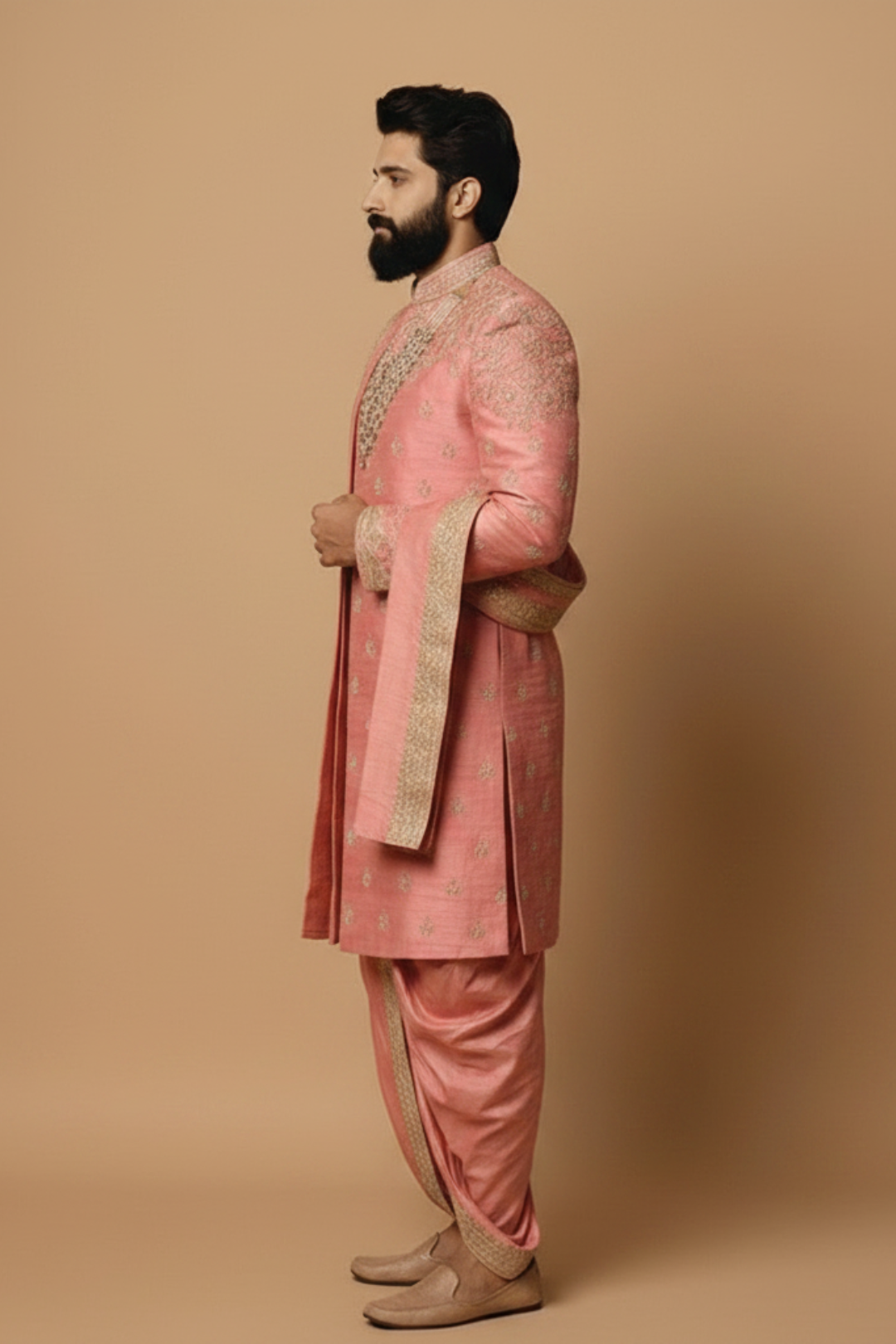 Man wearing a traditional pink sherwani with intricate embroidery on a beige background