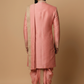 Man wearing a pink sherwani with a beige background