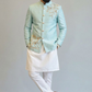 Man wearing a light blue embroidered jacket with white pants on a plain background