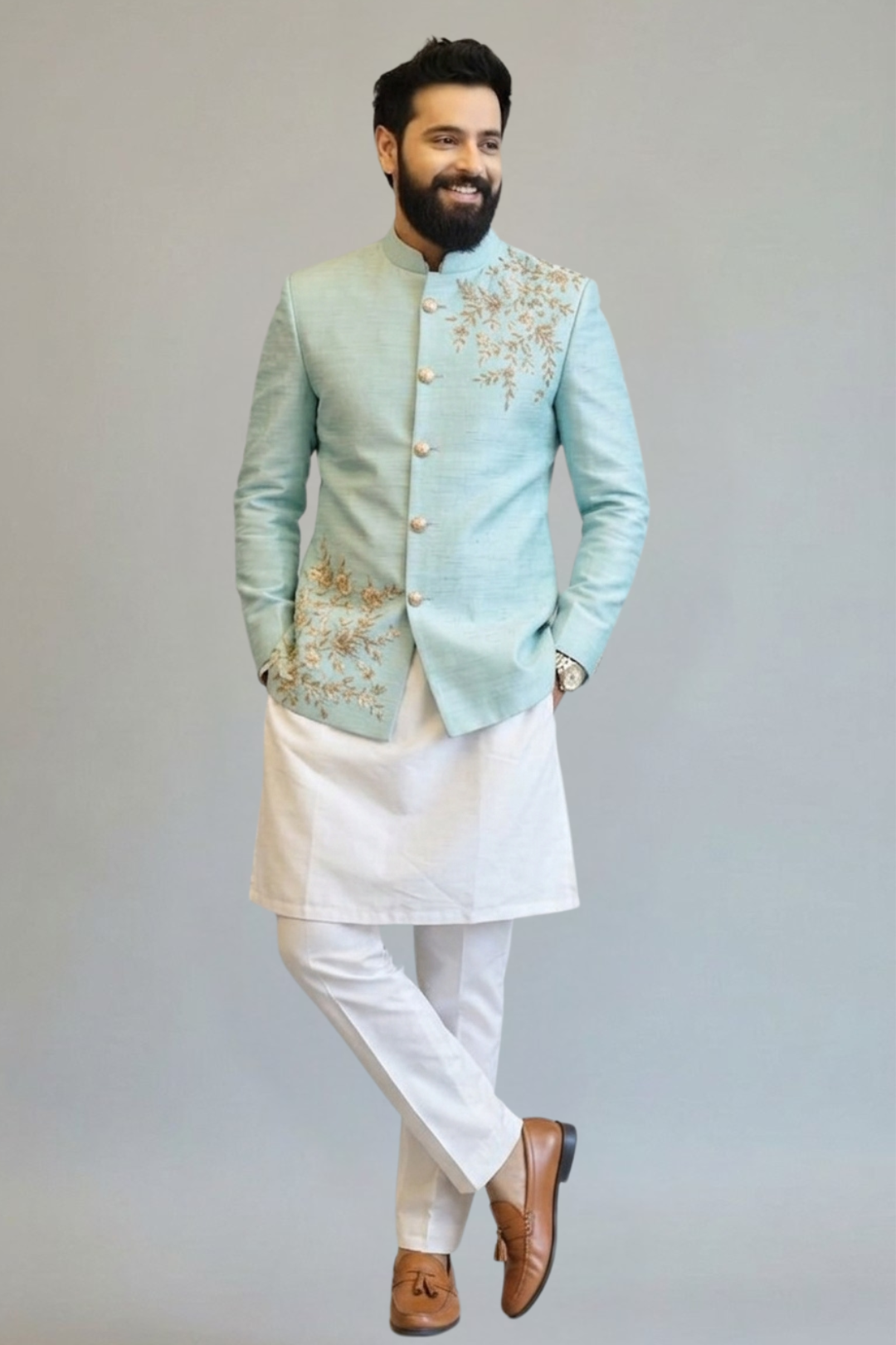 Man wearing a light blue embroidered jacket with white pants on a plain background