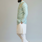 Man wearing a light blue embroidered jacket with white pants on a plain background
