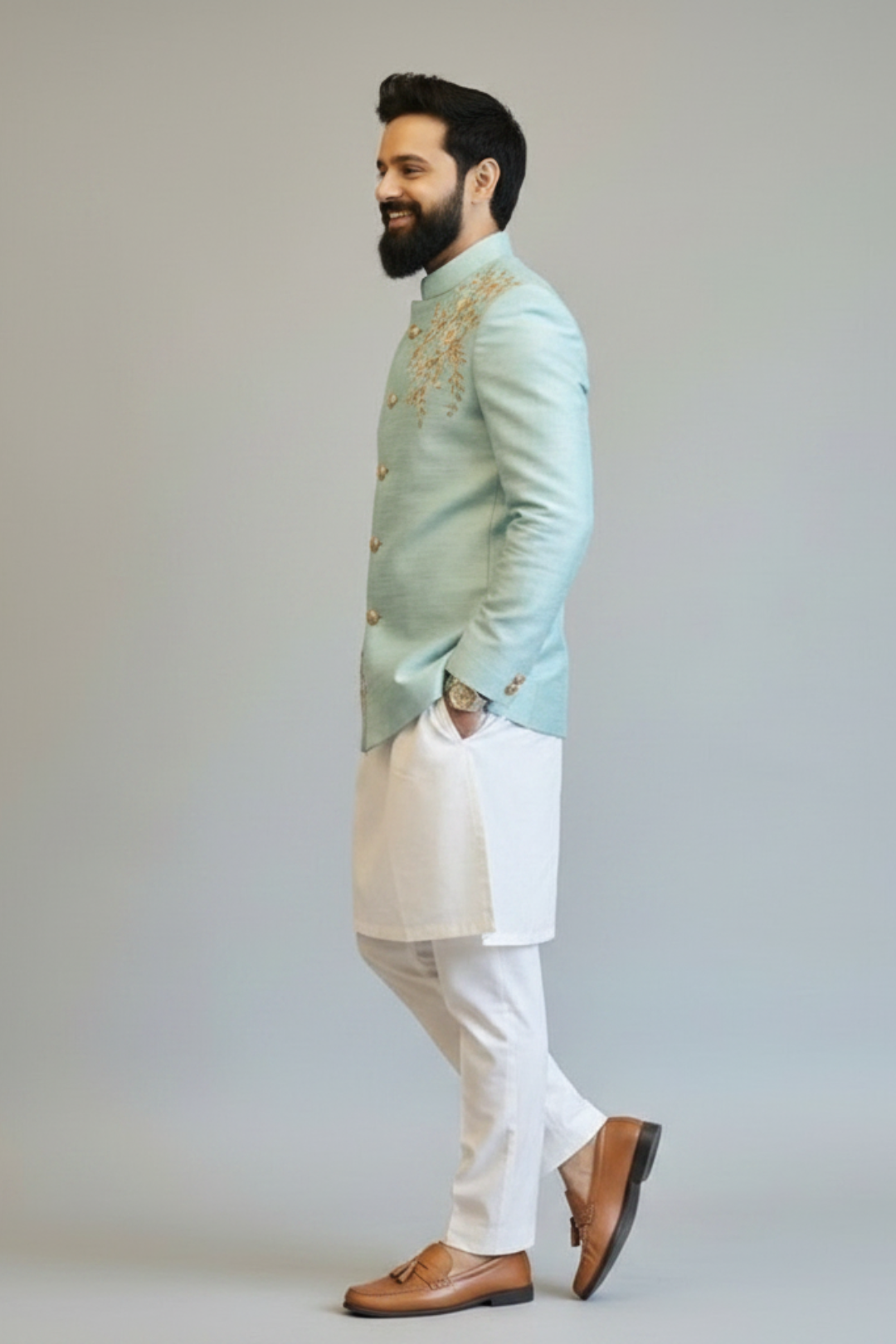 Man wearing a light blue embroidered jacket with white pants on a plain background