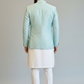 Man wearing a light blue jacket and white pants against a plain background