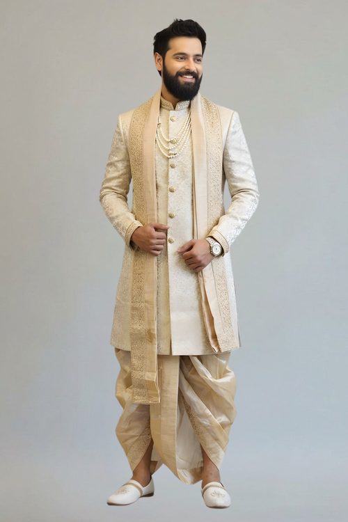 Man wearing a traditional beige sherwani with a plain background
