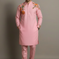 Man wearing a pink kurta with floral embroidery on a gray background