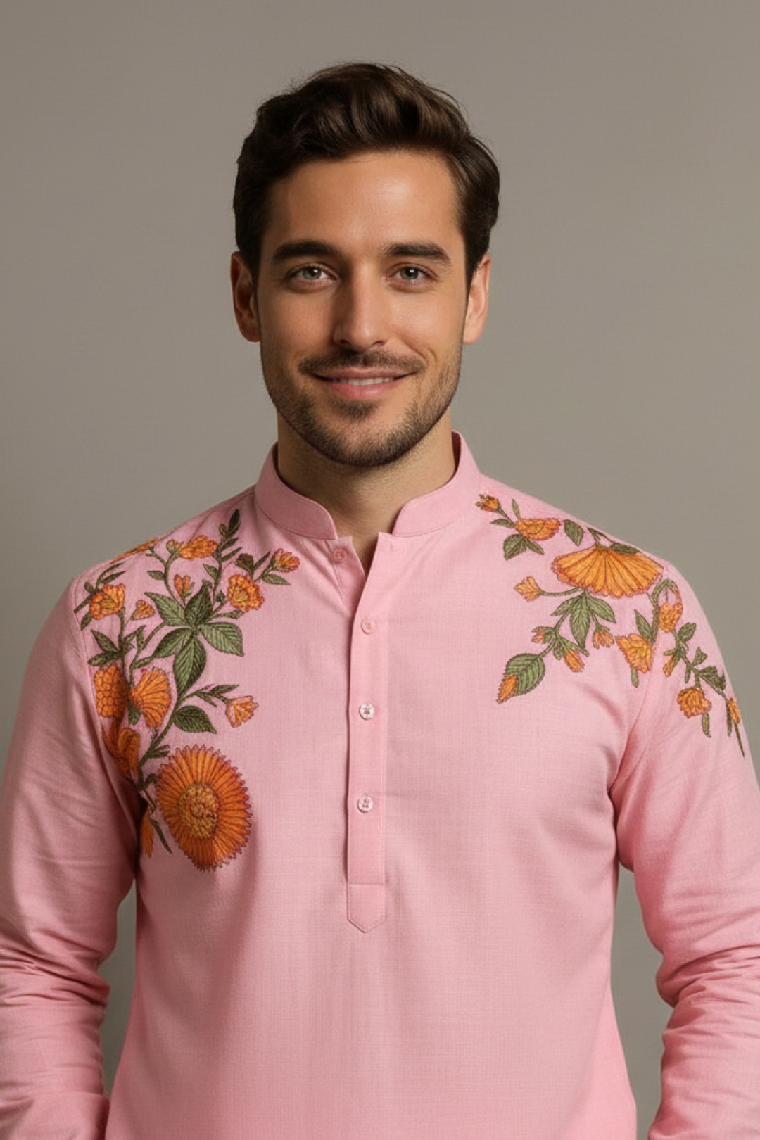 Man wearing a pink embroidered shirt against a plain background