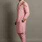 Man wearing a pink traditional outfit with floral embroidery on a gray background