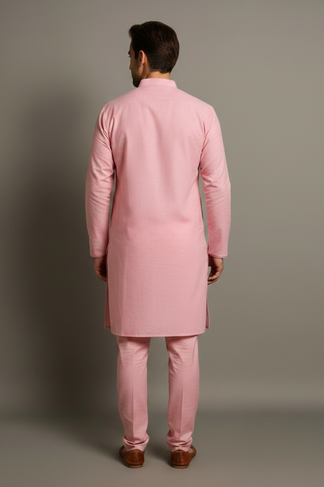 Man wearing a pink kurta with pants against a gray background