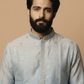 Man wearing a light blue embroidered kurta against a beige background