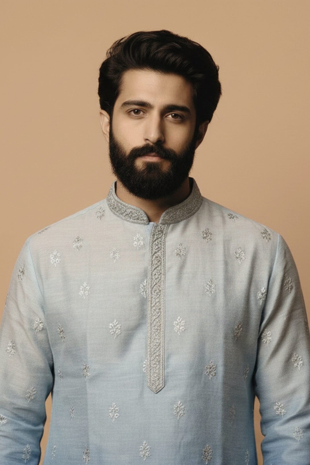 Man wearing a light blue embroidered kurta against a beige background