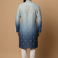 Man wearing a blue and gray gradient kurta with white pants on a beige background