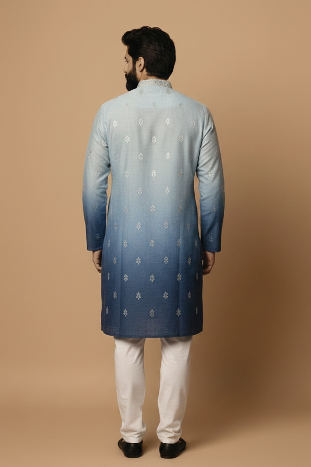 Man wearing a blue and gray gradient kurta with white pants on a beige background