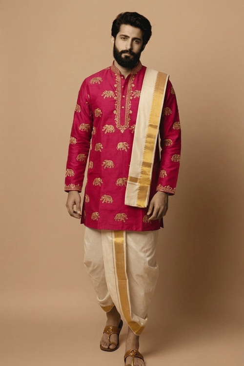 Man wearing a traditional pink kurta with gold embroidery and white dhoti on a beige background