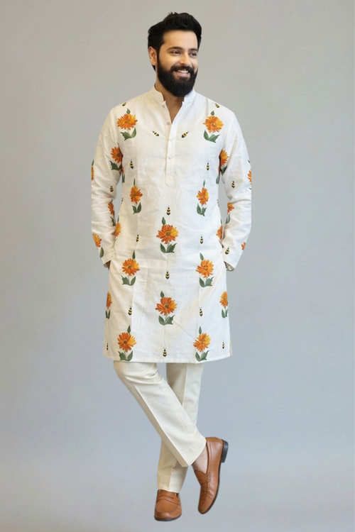 Man wearing a white kurta with floral patterns on a plain background