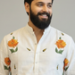 Man wearing a white kurta with floral patterns on a plain background