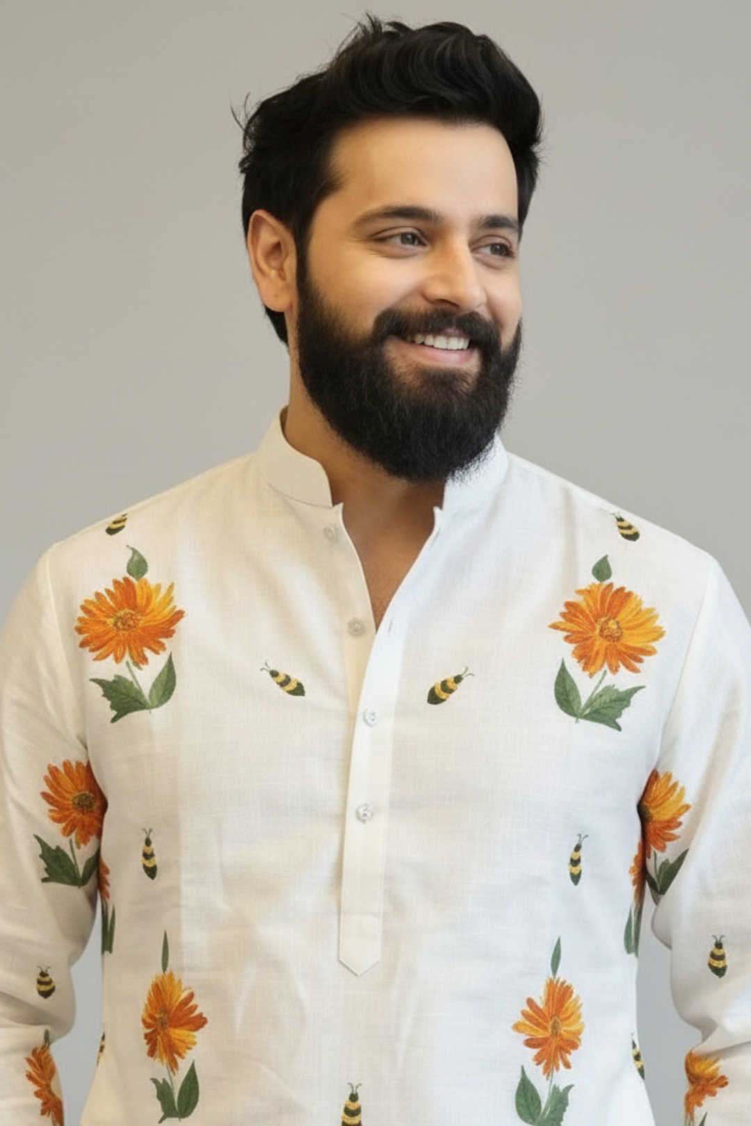 Man wearing a white kurta with floral patterns on a plain background