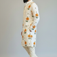 Man wearing a white kurta with floral patterns on a plain background