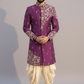 Man wearing a purple embroidered sherwani with white pants on a gray background
