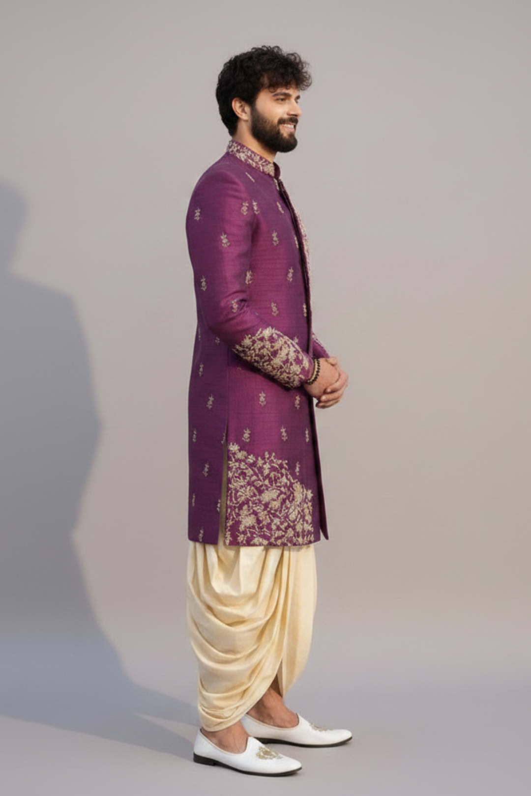 Man wearing a purple embroidered sherwani with beige dhoti on a plain background