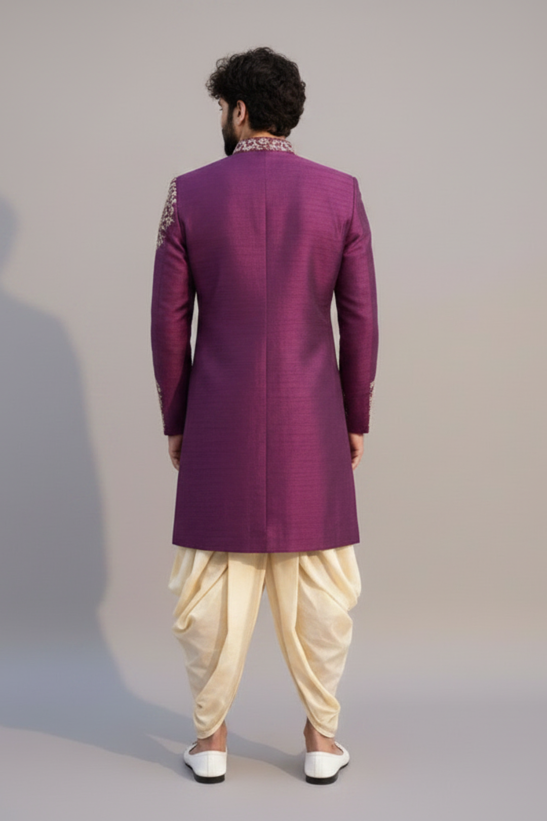 Man wearing a purple sherwani with white dhoti on a plain background