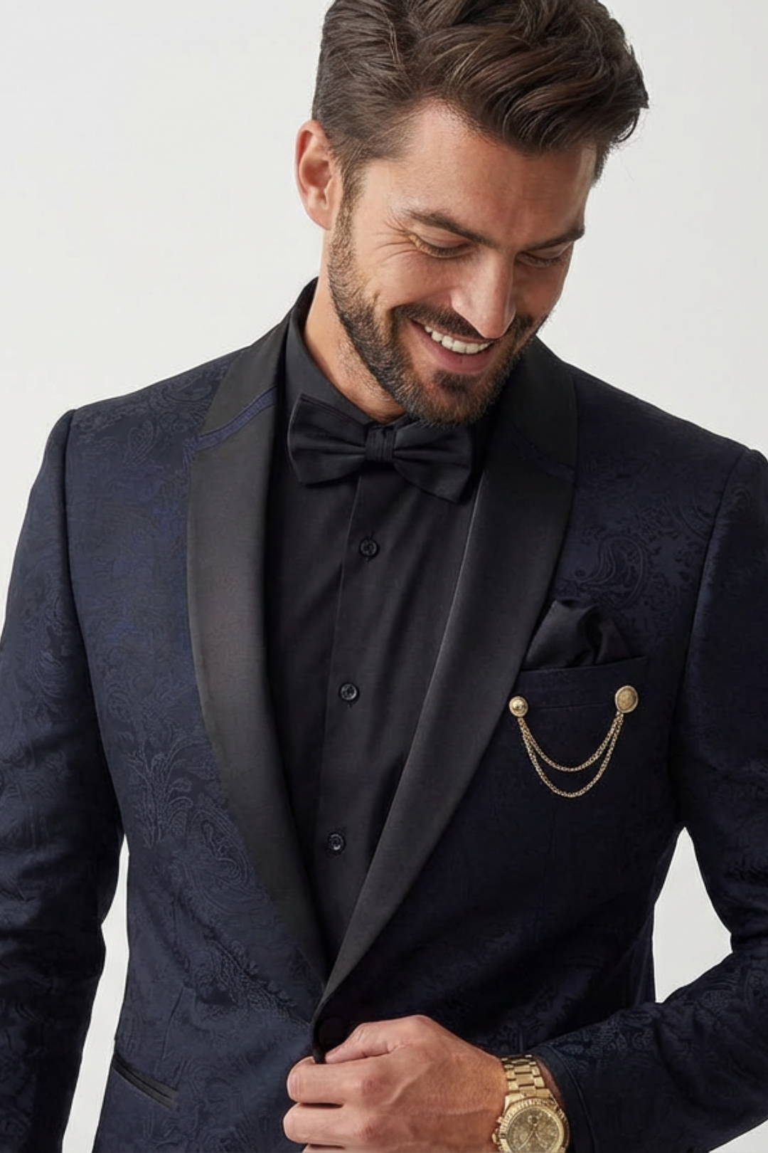Man wearing a dark blue tuxedo with a bow tie and pocket square on a white background