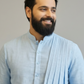 Man wearing a light blue kurta with a plain background