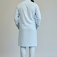 Man wearing a light blue kurta with white pants against a plain background