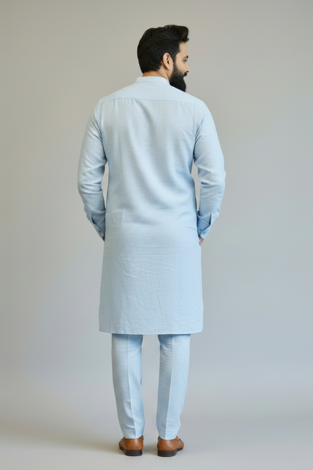 Man wearing a light blue kurta with white pants against a plain background