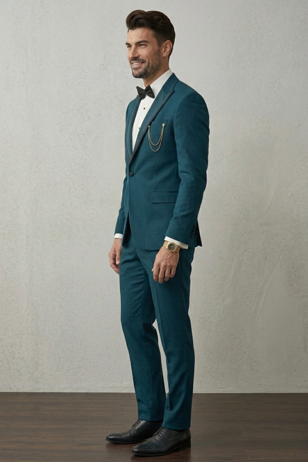 Man wearing a teal suit with a white shirt and black bow tie against a plain background