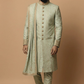 Man wearing a traditional light green sherwani with a matching turban on a beige background