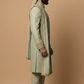 Man wearing a traditional sherwani with a turban on a beige background